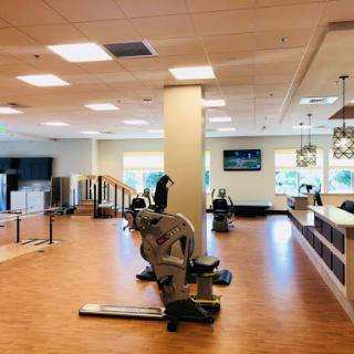 A spacious and well-lit rehabilitation gym featuring various exercise equipment and a welcoming interior.