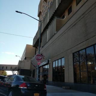 A view of a modern building with large windows and a stop sign on a city street.