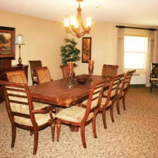A well-furnished dining room with a large table and chairs, illuminated by a chandelier.