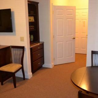 A cozy living room with seating, a TV, and a wooden shelving unit near an open door.