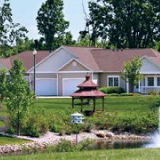 A serene landscape featuring a house, gazebo, and pond surrounded by lush greenery.