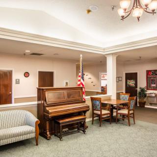 A well-furnished lobby featuring a piano, seating area, and an American flag.