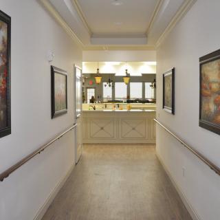 A well-lit hallway with artwork adorning the walls leads to a reception area.