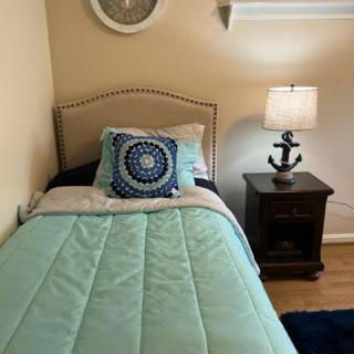 A cozy bedroom corner with a neatly made bed, bedside lamp, and nightstand.