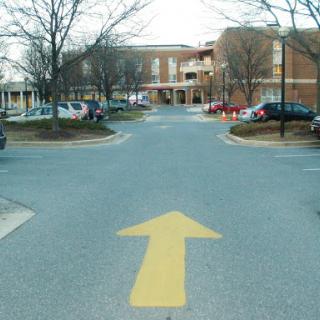 A view of a parking lot with a clear directional arrow pointing straight ahead.