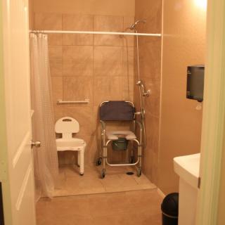 Accessible bathroom with a shower chair and tiled walls.