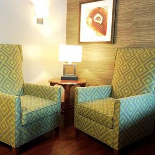 A cozy living room setup featuring two stylish armchairs, a small lamp on a wooden table, and artwork on the wall.