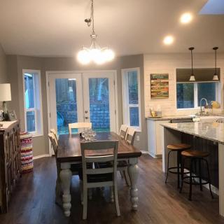 A modern kitchen and dining area with an open layout, featuring wood flooring and stylish lighting.