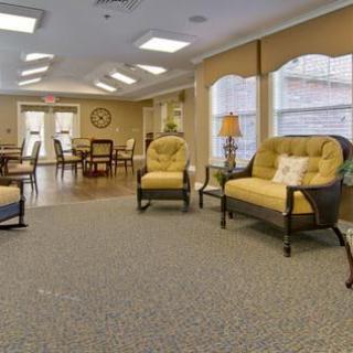 A cozy lounge area with comfortable chairs and a sofa, well-lit by large windows.