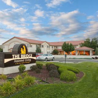 A hotel building with a sign reading 'The Ridge' surrounded by well-maintained gardens and a cloudy sky backdrop.