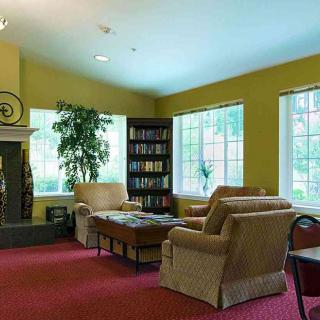 A cozy living room with armchairs, a fireplace, and a bookshelf.
