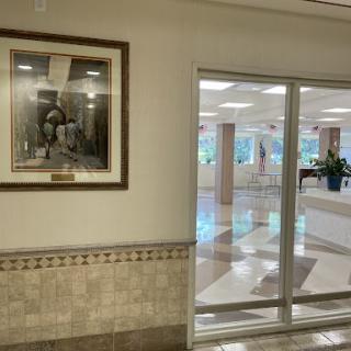 A well-lit corridor featuring a framed photograph and glass doors leading to another area.