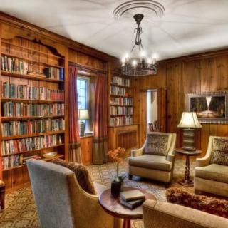 A cozy library with wood paneling, bookshelves, and comfortable armchairs.