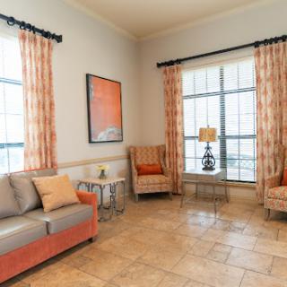 A cozy living room featuring a comfortable sofa and armchairs, adorned with stylish curtains and decorative artwork.