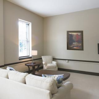 A cozy living room with a sofa, armchair, coffee table, and artwork.