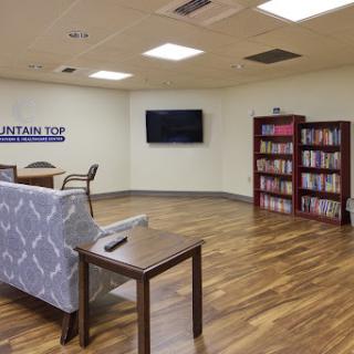 A cozy lounge with comfortable seating, a television, and a bookshelf filled with books.