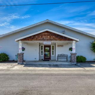 The exterior of a funeral home with white siding and a front entrance under a gabled roof.