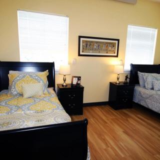 A cozy bedroom with two beds, nightstands, and warm lighting.