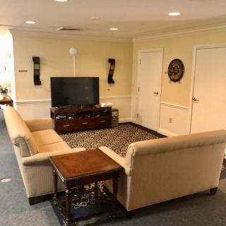 A cozy living room with a beige sectional sofa, a patterned carpet, and a television set in front of the seating area.