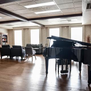 A spacious living room featuring a grand piano and modern furniture.
