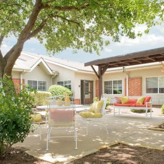 A sunny patio with comfortable seating surrounded by a lush garden.