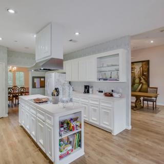 A modern kitchen with white cabinets and a central island, featuring an open concept dining area.