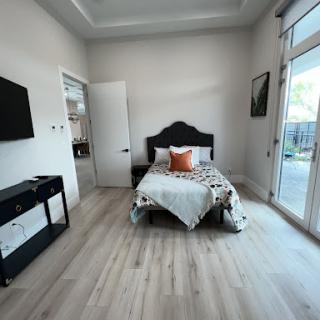 A stylish and minimalist bedroom featuring a cozy bed, ample natural light, and modern decor.