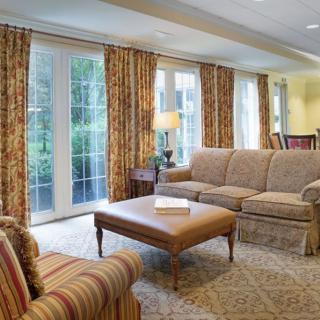 A cozy living room with patterned curtains, a comfortable sofa, and a center table.