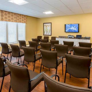 An empty conference room set up for presentations with rows of chairs facing a television.