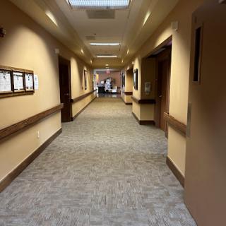 A view of a well-lit hallway with doors on either side, featuring carpeted flooring.