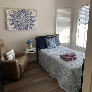 A cozy and well-decorated bedroom featuring a bed, recliner chair, and wall art.
