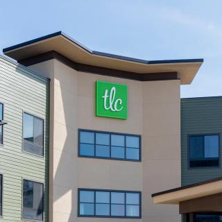 Photo of a building exterior with a green TLC sign.