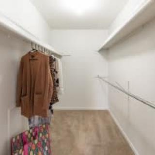 A minimalist walk-in closet with a few hanging clothes on the left.