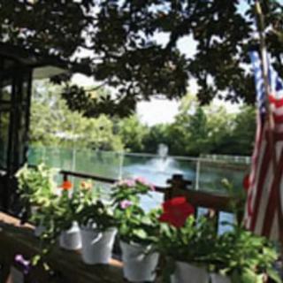 A scenic patio overlooking a lake, adorned with plants and an American flag.