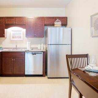 A modern kitchen with stainless steel appliances and wooden dining furniture.