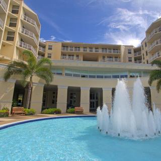 A luxurious hotel with a central fountain and surrounding palm trees.