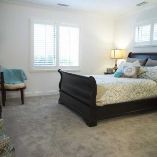 A cozy bedroom with a large bed, plush carpeting, and elegant decor.