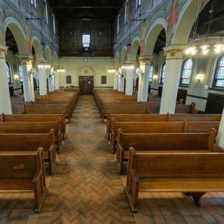 Interior view of a church with wooden pews and arched architecture.
