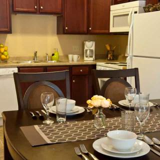 A cozy kitchen with a neatly set dining table, featuring dishes, glasses, and cutlery.