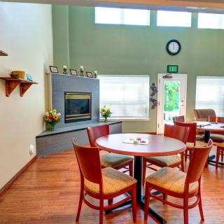 A cozy dining area with a round table, chairs, and a fireplace in a modern interior setting.