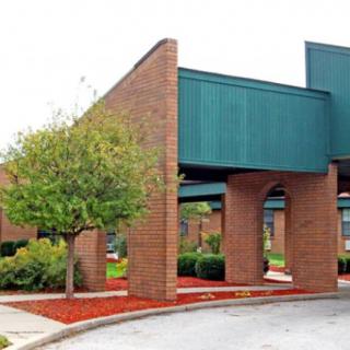 A modern brick building with green accents and landscaped surroundings.