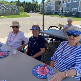 A group of seniors enjoying an outdoor social event at a picnic table.