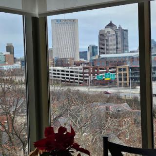 A view of the city skyline framed by a window, showcasing urban buildings and a hint of greenery.