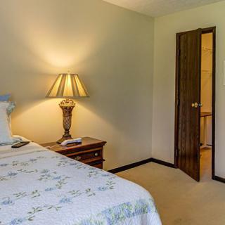 A cozy bedroom featuring a bed with a patterned quilt, a nightstand, and a decorative lamp.