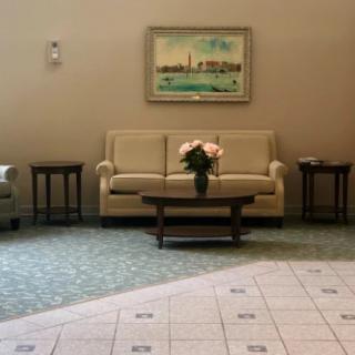 A cozy lobby area featuring a sofa, coffee table with flowers, and artwork on the wall.