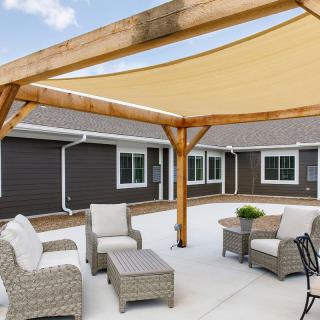 A comfortable outdoor patio with wicker seating and a wooden shade structure.