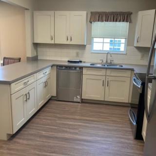 A modern kitchen with white cabinets, stainless steel appliances, and a hardwood floor.