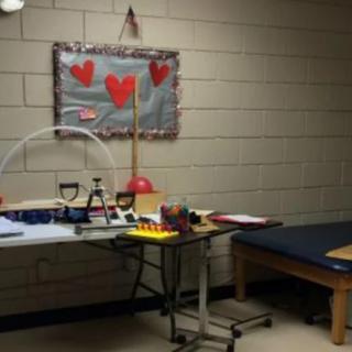 A therapy room equipped with exercise tools and a treatment table, decorated with heart-themed artwork.