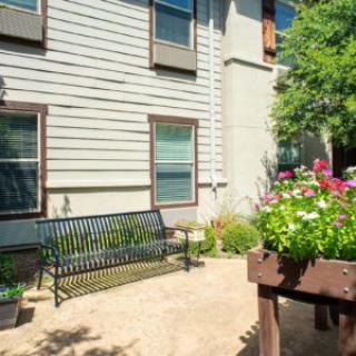 A peaceful garden area with a bench and colorful flowers in front of a building.