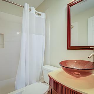 A modern bathroom featuring a glass sink and a shower with a white curtain.